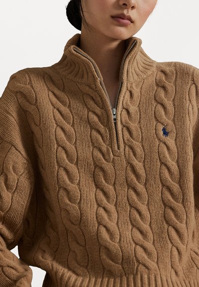 Maglione zip-up in marrone a treccia, con design testurizzato, colletto alto e un piccolo logo blu sul petto. Materiale morbido simile alla lana.