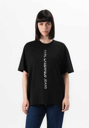 Maglietta nera in cotone con maniche corte. Presenta la scritta verticale bianca "KARL LAGERFELD JEANS" stampata al centro. Design semplice.