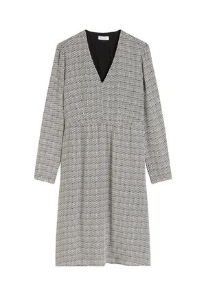 Personne portant une robe mi-longue à manches longues avec un petit motif en zigzag noir, associée à des chaussettes noires et des mocassins à plateforme noirs.