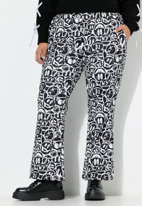 Zwart-gewitte gestreepte broek met verschillende expressieve gezichten, een losse pasvorm en een elastische tailleband. Gemaakt in combinatie met zwarte plateau schoenen.