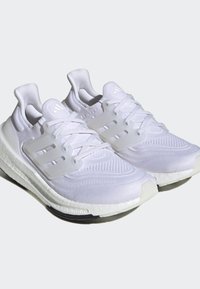 Witte sportschoenen met een geweven bovenkant van textuur, doorzichtige plastic accenten, een gevoerde zool en ton-sur-ton veters. Bevat een prominent logo.