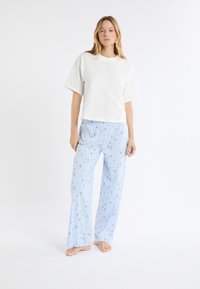 Biała bawełniana koszulka z krótkim rękawem, w zestawie z jasnoniebieskimi spodniami do piżamy z kwiatowym wzorem i elastycznym pasem.