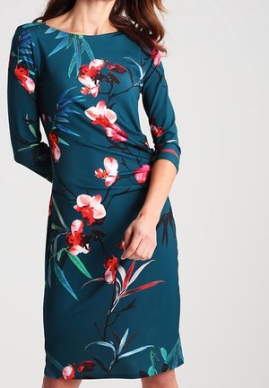 Teal bloemenjurk met een aansluitende pasvorm, driekwartmouwen en een botanische print met roze en rode bloemen op een gladde stof.