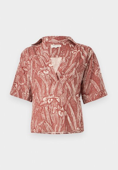 Blouse rouge rouille à manches courtes avec imprimé botanique blanc, col ouvert et coupe ample.