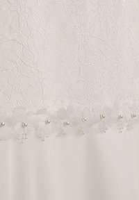 Weißer Spitzenstoff mit Blumenmustern, verziert mit Perlendetails und zarten Perlenbesätzen am Saum. Strukturierte Oberfläche.