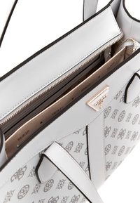 Sac à main en simili cuir gris avec un design à motifs, double poignée supérieure et fermeture éclair dorée. Comprend des compartiments intérieurs et un branding.
