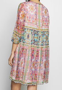 Vestido colorido y estampado con un diseño acampanado. Confeccionado en tela ligera, presenta mangas tres cuartos y un dobladillo de volantes.