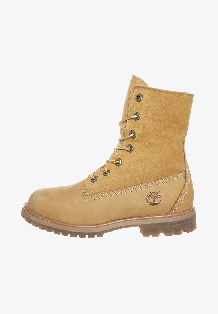 Botte en cuir fauve à lacets avec œillets métalliques, semelle en caoutchouc robuste et logo arbre Timberland sur le côté.