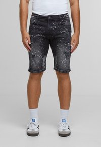Džínové kraťasy v černé barvě s vybledlým vzhledem; s odřenými částmi a vzorem stříkanců; slim fit, do kolen, s pěti kapsami.