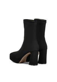 Stivaletti neri alla caviglia con una finitura in tessuto liscio, punta rotonda e tacco alto squadrato. Presentano una suola con piattaforma e un design aderente alla caviglia.