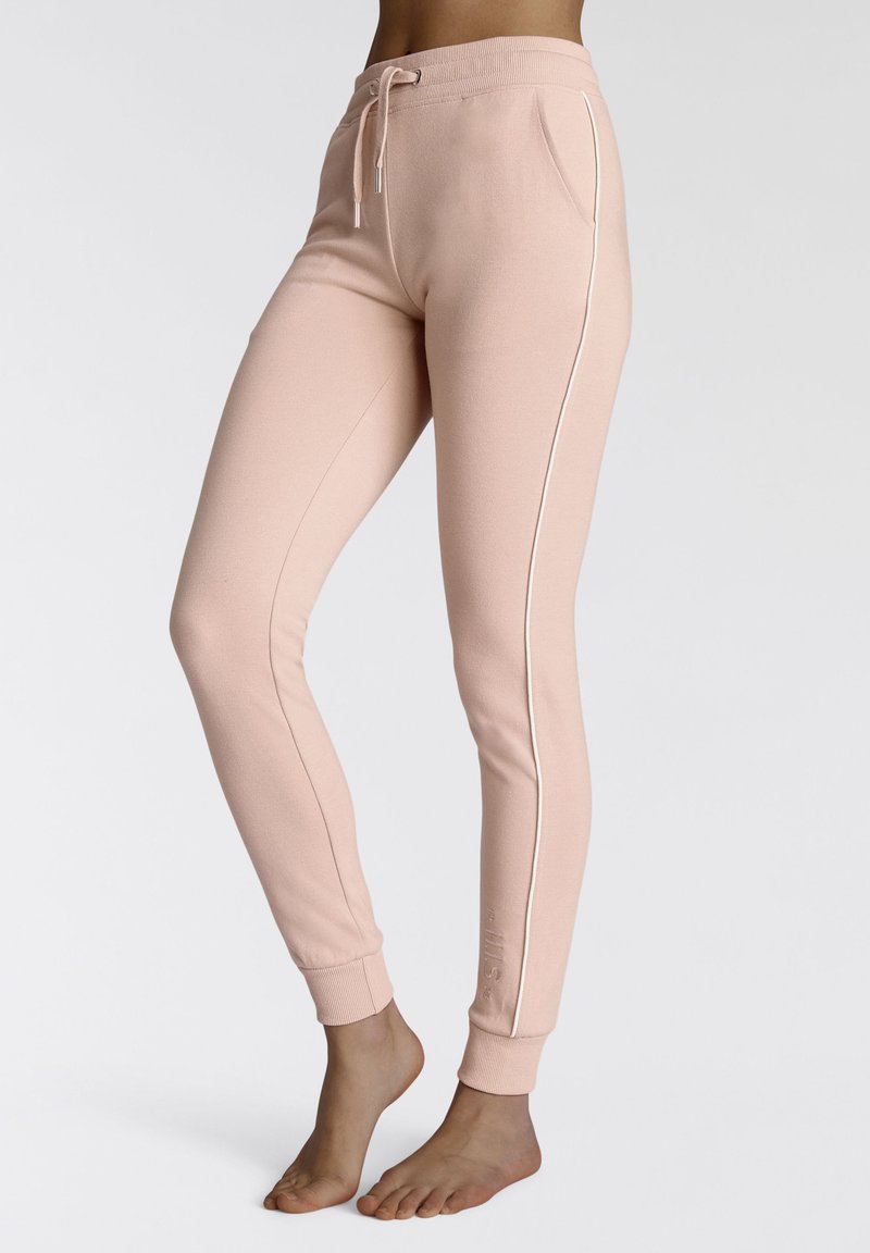 Helle rosa Sweatpants mit einem Kordelzugbund, schmalem Schnitt, seitlichen Taschen und weißen, kontrastierenden Seitenstreifen. Weicher Stoff und gerippte Bündchen.