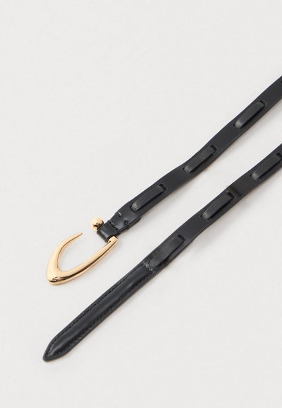 Musteknahkainen hihna, jossa on useita silmukoita ja kultainen kaareva koukku kiinnitys, vaalealla taustalla.