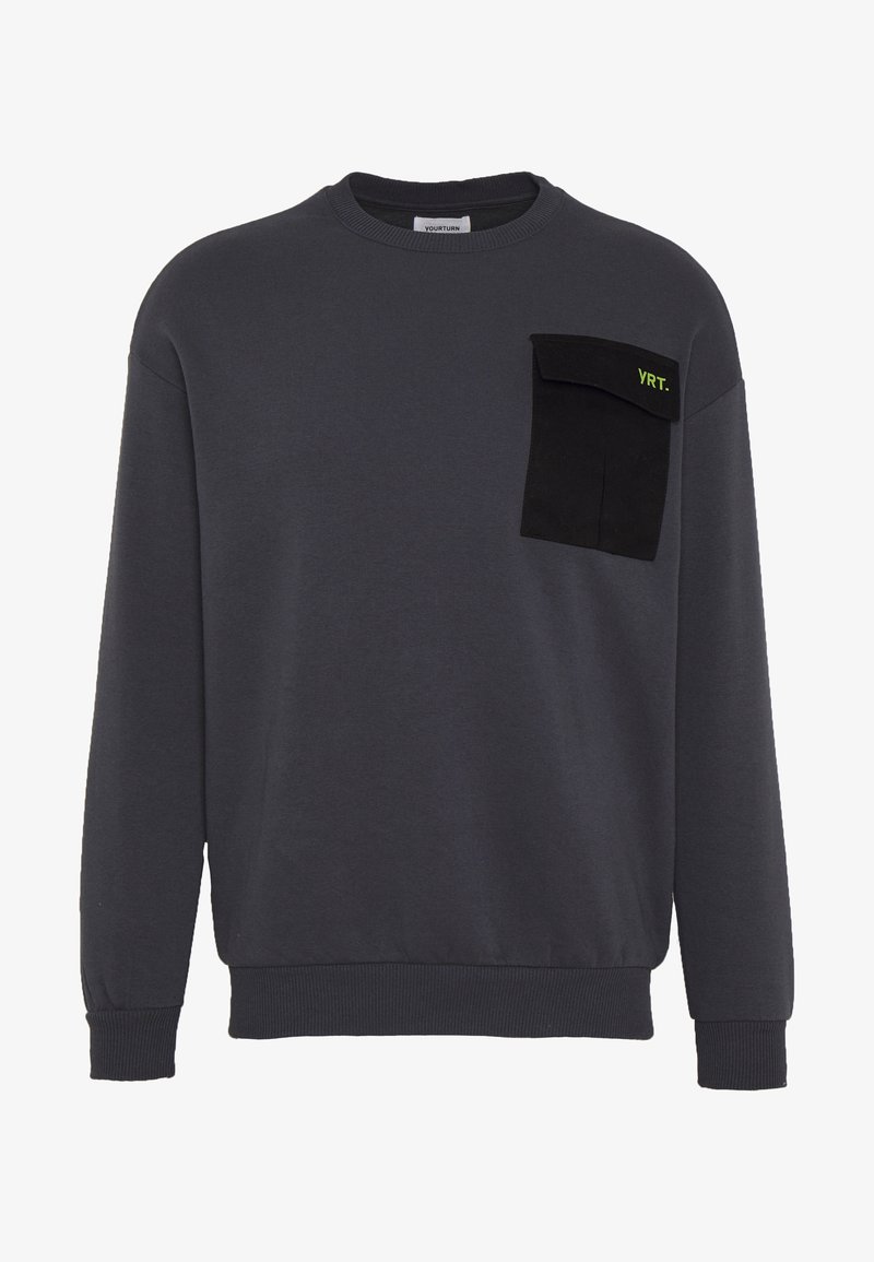 Sweat-shirt gris foncé à col rond avec manches longues et une poche à rabat noire sur la poitrine gauche, avec le texte "YRT." en vert.