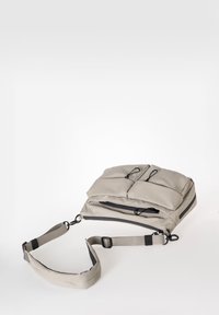 Helle graue Umhängetasche mit gepolstertem Design, zwei Vordertaschen, einem Reißverschluss und einem verstellbaren Schulterriemen. Glatte Textur.