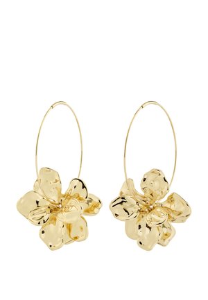 Złote kolczyki-koła z nieregularnymi, teksturowanymi zawieszkami w kształcie kwiatów, zawieszonymi wewnątrz każdego koła.