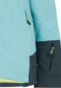 Helle blaue Jacke mit dunkelblauen Akzenten, ausgestattet mit Reißverschluss-Taschen und kontrastierender gelber Fütterung am Saum. Wasserabweisender Stoff.