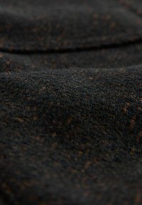 Tânără și neagră, țesătura din lână texturată are o suprafață moale, ușor pufoasă și un model de mici stropi pe tot parcursul ei.