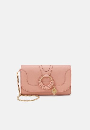 Pochette en cuir rose avec bandoulière chaîne dorée, anse circulaire tressée et petit charm doré à l'avant.
