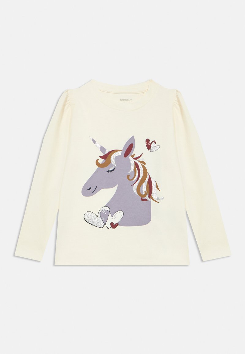 Camicia crema a maniche lunghe con grafica di un unicorno grigio con criniera colorata e cuori, realizzata in morbido cotone. Dettagliata con accenti glitterati.