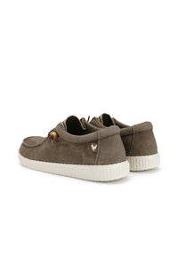 Scarpe in suede marrone con lacci elastici, suola in gomma bianca a contrasto e un piccolo patch con logo sul tallone. Design con punta arrotondata.