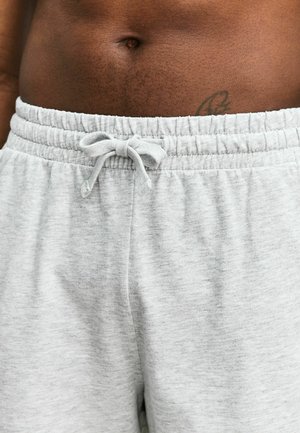 Lichtgrijze joggingbroek van zacht materiaal, met een elastische tailleband en een trekkoord, en een gladde textuur. Geen zichtbare zakken.