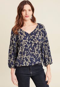 Bloemige blouse in olijfgroen met marineblauwe patronen; V-hals, losse mouwen met elastische manchetten, zachte stof en knoopdetails.