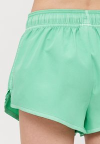 Menta zöld, könnyű sort, rugalmas derékkal. Oldalsó hasítékokkal a szabad mozgás érdekében és sima tapintással rendelkezik.