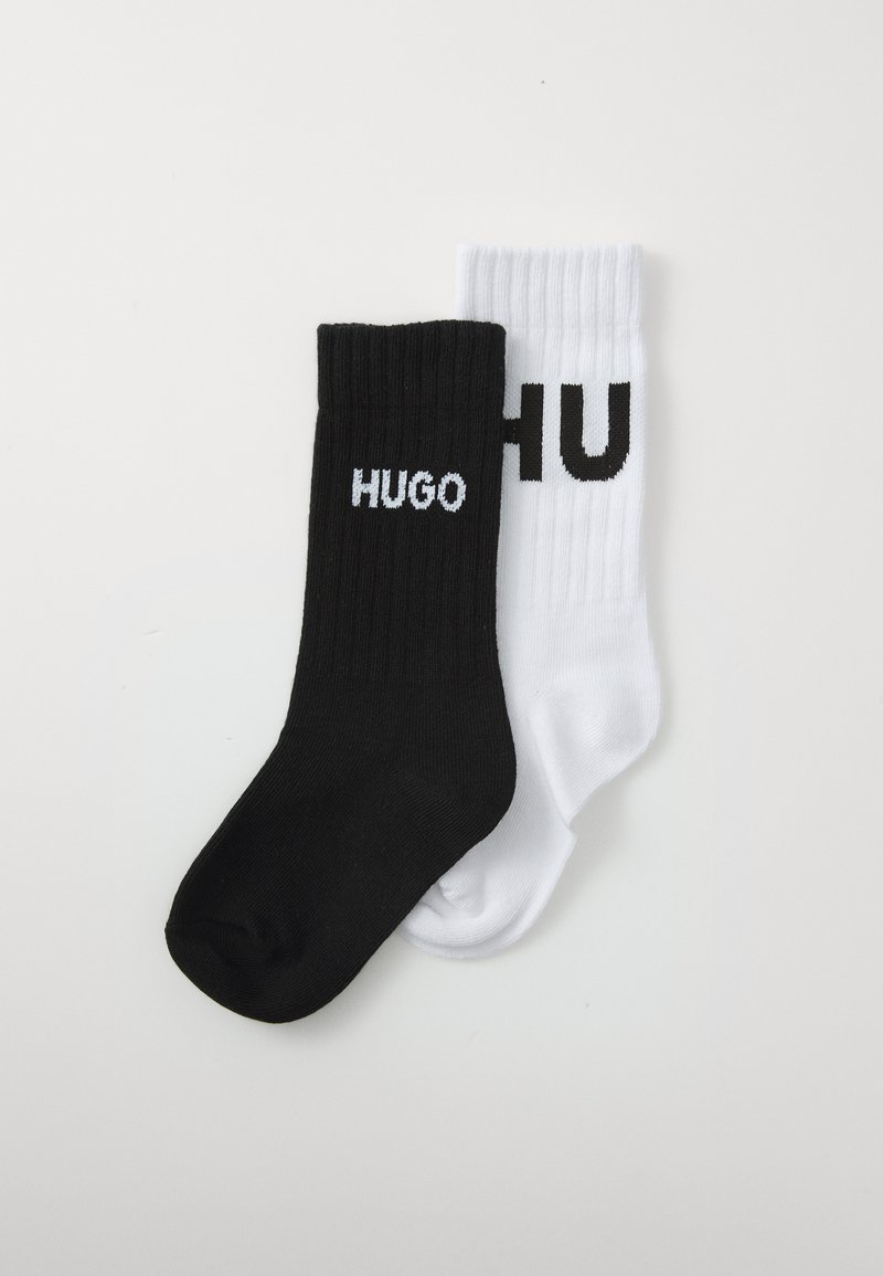 Calcetines de crew de rayas en blanco y negro que presentan la palabra "HUGO" en colores contrastantes, con letras negras sobre el calcetín blanco y letras blancas sobre el calcetín negro.
