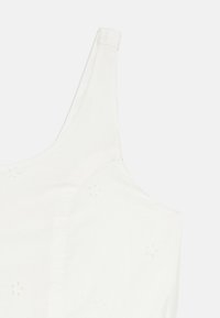 Vêtement blanc sans manches, gros plan sur la partie supérieure avec des motifs floraux en broderie anglaise et fines bretelles.