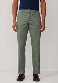 Pantalon en coton vert à coupe décontractée, avec une braguette zippée et une fermeture par bouton, des jambes droites et des poches latérales.