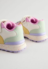 Baskets d'enfant en blanc, vert clair et jaune. Tige en tissu texturé, col rembourré rose et semelle éclaboussée en bleu et rose.