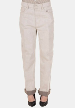 Pantaloni beige a gamba dritta con orli risvoltati indossati con tacchi neri a punta e una camicia a righe infilata dentro.
