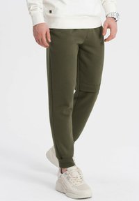 Olijfgroene joggers van textuurstof, met een slim-fit ontwerp, elastische boorden en een zijzak voor functionaliteit.