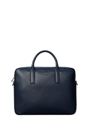 Mallette en cuir bleu foncé avec deux poignées et une fermeture éclair, forme rectangulaire, design minimaliste, petit logo de la marque à l'avant.