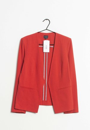 Dopasowana czerwona damska marynarka z długimi rękawami, otwartym przodem, dwoma przednimi kieszeniami, wisząca na czarnym wieszaku z białą metką cenową.