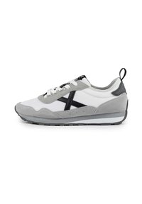 Zapatillas con una parte superior de malla blanca y acentos de ante gris, logo negro y detalles, cordones blancos planos y una suela texturizada gris.