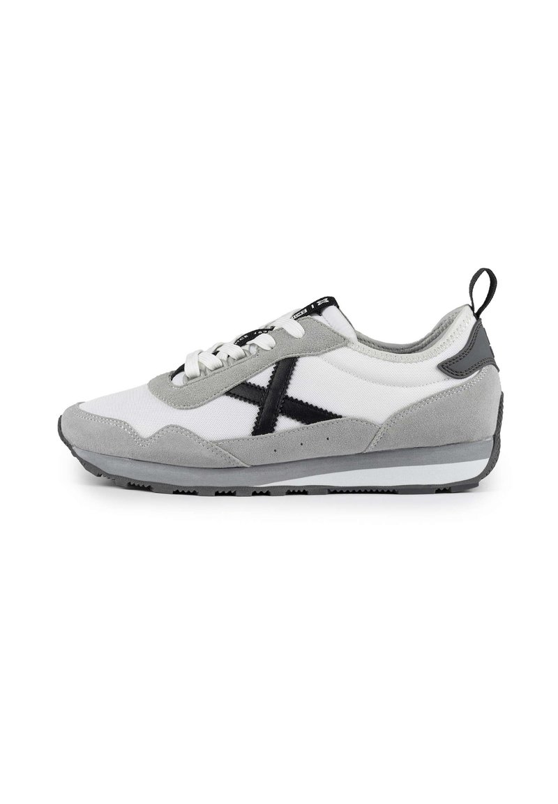 Zapatillas con una parte superior de malla blanca y acentos de ante gris, logo negro y detalles, cordones blancos planos y una suela texturizada gris.