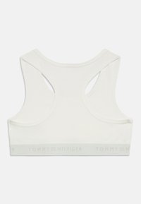 Hvit sports-bh med racerback-design, laget av mykt stoff. Har et merkeband nederst med "TOMMY HILFIGER" i lys grå.