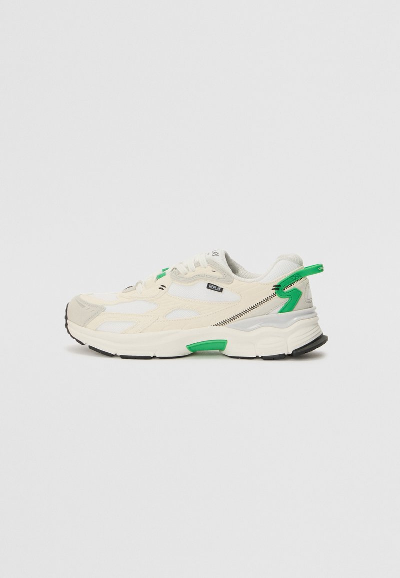 Sneaker con una toma superiore in rete di color crema e grigio chiaro, dettagli verdi, suola in gomma nera e cuciture a contrasto. Presenta una chiusura con lacci.