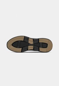 Suela de zapato de goma negra con una superficie texturizada que presenta una entresuela beige. Diseñada con ranuras para tracción y estabilidad.
