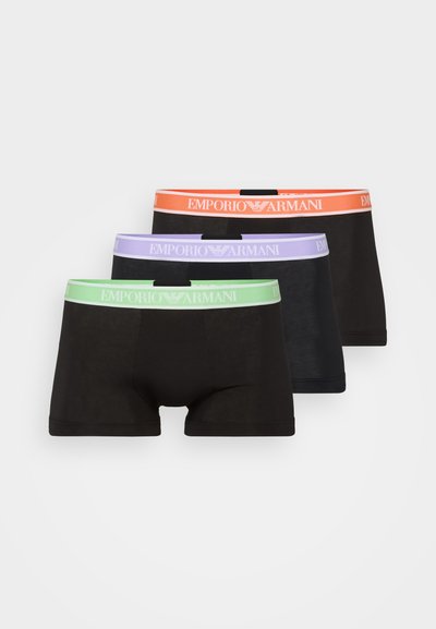 Trois paires de boxers noirs avec des ceintures élastiques orange, vert et violet, portant le logo « Emporio Armani » bien en évidence.