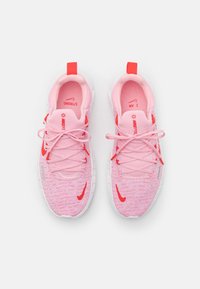 Pár růžových a červených běžeckých bot Nike s bílými podrážkami, viděný shora, s síťovinovou tkaninou a viditelnými tkaničkami.