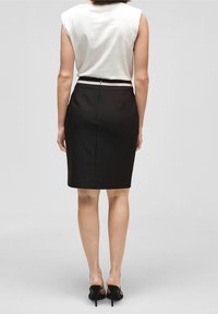 Černá tužková sukně s přiléhavým střihem, zadním zipem a decentním bílým pasem. Hladký materiál s elegantní siluetou.