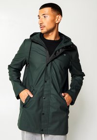 Green waterproof jacket with a hood, featuring a zippered front, black accents, and side pockets. Smooth texture with a modern silhouette.