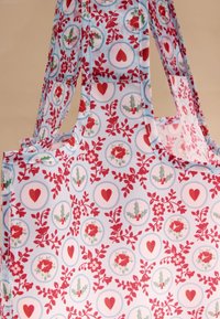 Mintás, könnyű anyagból készült bevásárlótáska. Világoskék alapon piros szívek, virágok és magyal díszítik, erős vállpántokkal.