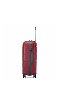 Hard-shell suitcase in red with a textured design, featuring a retractable handle and four wheels for easy mobility. Zipper closure with a lock.
