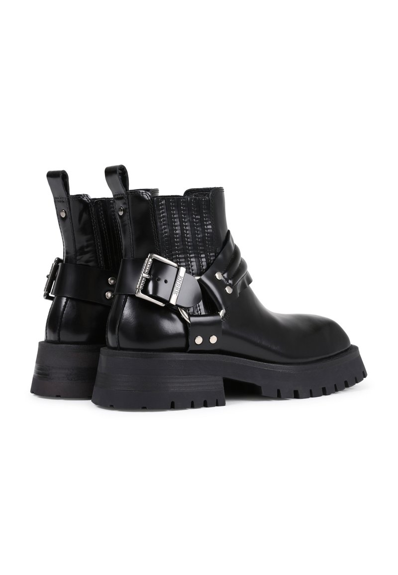 Schwarze Leder-Ankle-Boots mit einem strukturierten schwarzen Einsatz, silberner Schnallen-Detail, dicker Gummisohle und Zugschlaufen an der Rückseite für ein einfaches An- und Ausziehen.