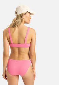 Pink ribbed bikini with thick straps and a scoop-back design. The set includes a matching bottom with a mid-rise cut and subtle branding detail.