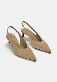 Tacchi slingback beige in suede con punta affusolata e tacco basso a blocco. Presentano un'apertura a forma di V e una superficie in tessuto texture.