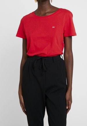 Czerwona bawełniana koszulka z okrągłym dekoltem, krótkimi rękawami i małym logo na piersi, połączona z czarnymi spodniami z wysokim stanem.